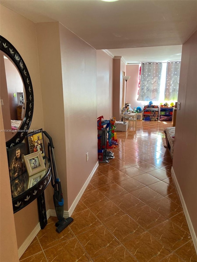 hall with dark tile floors and ornamental molding