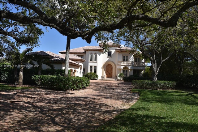 mediterranean / spanish home featuring a balcony and a front lawn