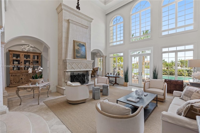 living room featuring french doors, a wealth of natural light, a towering ceiling, and a premium fireplace