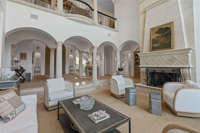 living room with a towering ceiling, decorative columns, and a tile fireplace