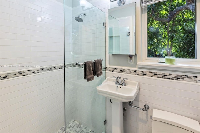 bathroom featuring tile walls, sink, toilet, and tiled shower