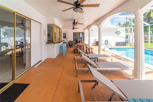 view of patio featuring ceiling fan and glass enclosure