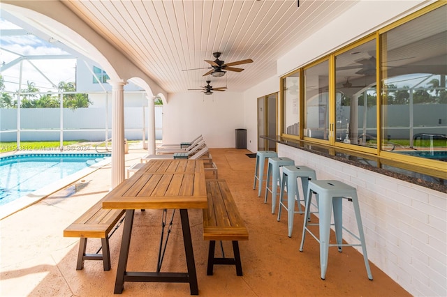 view of terrace with a bar, ceiling fan, and a fenced in pool