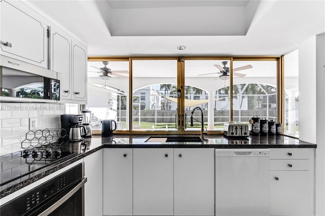 kitchen with a healthy amount of sunlight, tasteful backsplash, stainless steel appliances, and white cabinetry