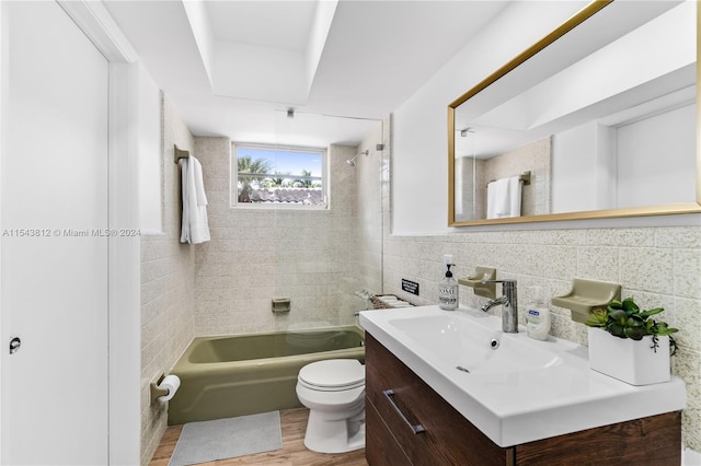 full bathroom with tile walls, tiled shower / bath combo, toilet, hardwood / wood-style floors, and vanity