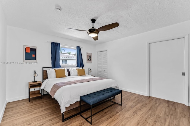 bedroom featuring ceiling fan, a closet, light hardwood / wood-style flooring, and a textured ceiling