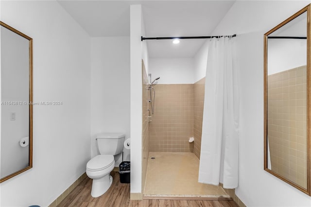 bathroom featuring curtained shower, toilet, and hardwood / wood-style flooring