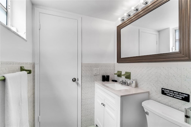 bathroom with vanity with extensive cabinet space, toilet, and tile walls