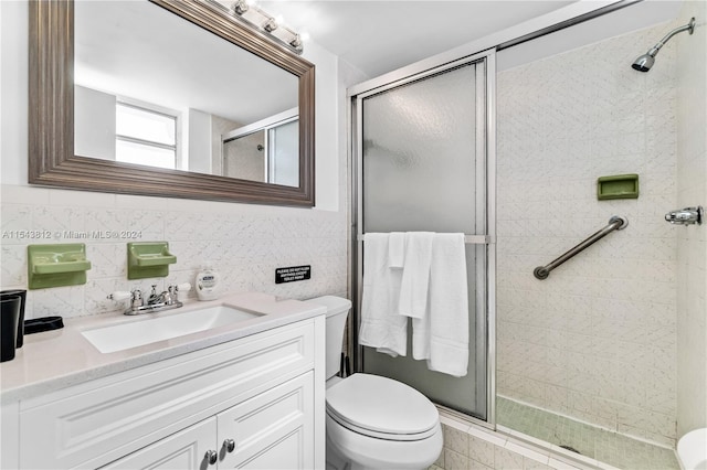 bathroom featuring tile walls, oversized vanity, toilet, and a shower with door