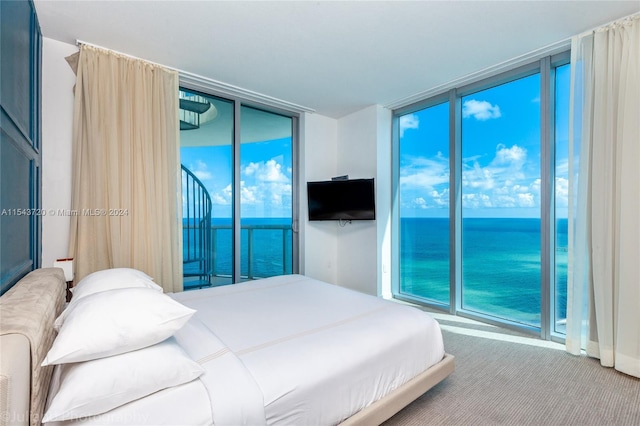 bedroom featuring a water view and a wall of windows