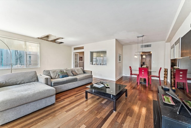 living room with dark hardwood / wood-style floors and an inviting chandelier