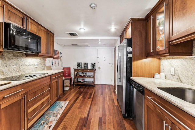 kitchen featuring dark wood-type flooring, light stone counters, black appliances, and tasteful backsplash