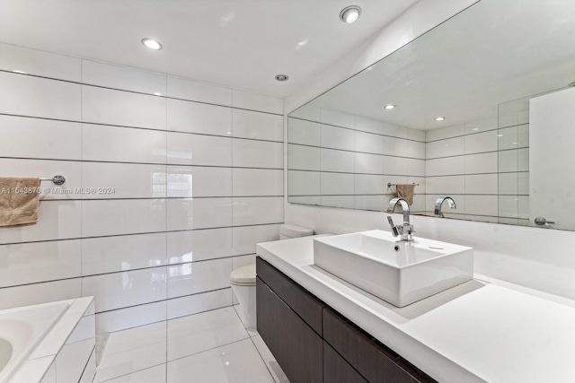 bathroom with toilet, vanity, tiled bath, tile walls, and tile floors