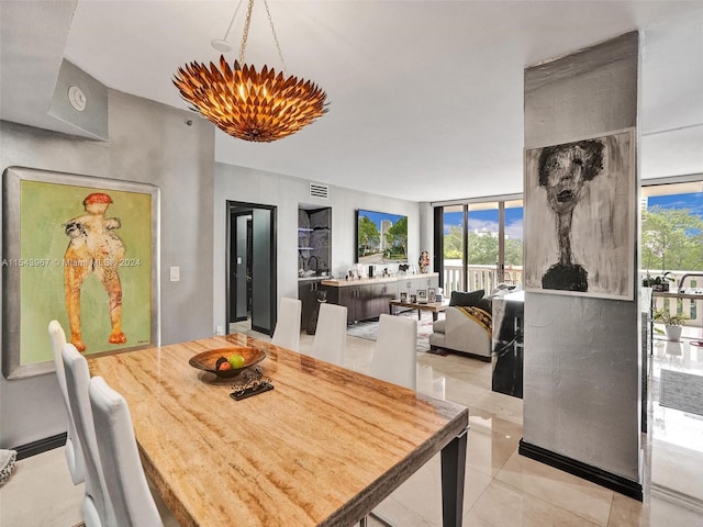 tiled dining area featuring a chandelier and a wall of windows