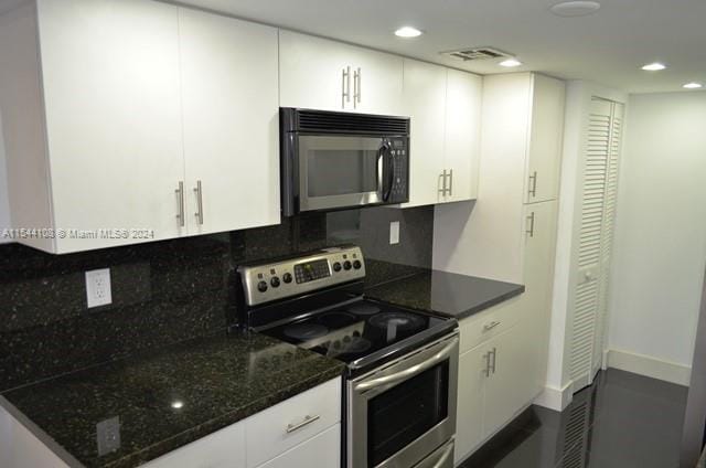 kitchen featuring electric stove, backsplash, and white cabinetry