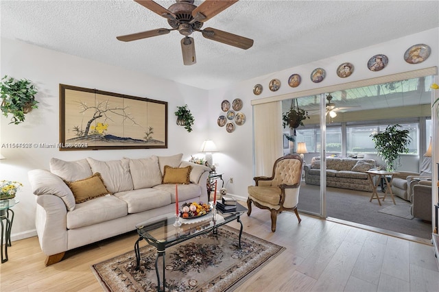 living room with light hardwood / wood-style floors, a textured ceiling, and ceiling fan