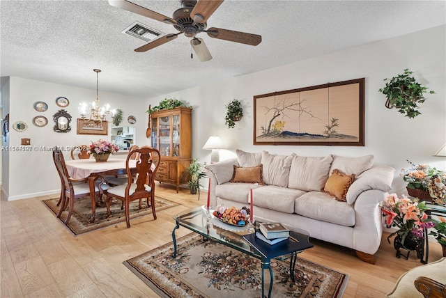 living room featuring light hardwood / wood-style flooring, a textured ceiling, and ceiling fan with notable chandelier