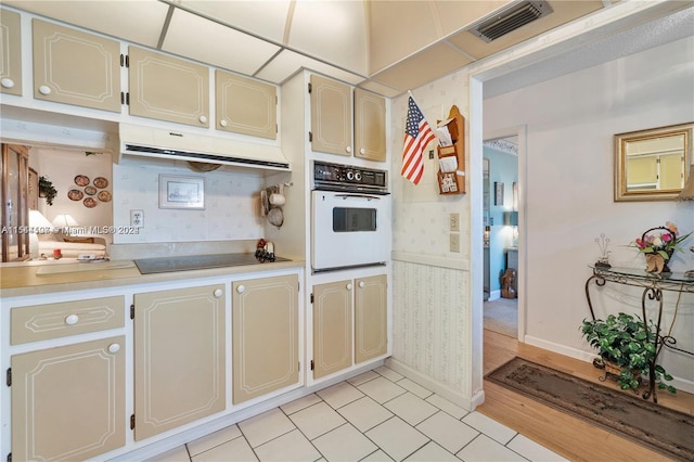 kitchen featuring oven, black electric stovetop, and light hardwood / wood-style flooring