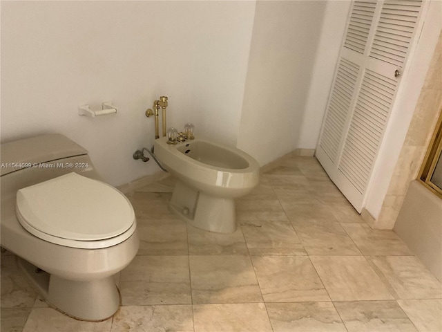 bathroom with a bidet, tile floors, and toilet