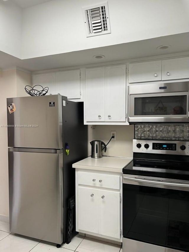 kitchen featuring light tile floors, white cabinets, and stainless steel appliances