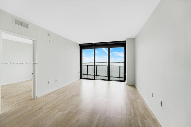 unfurnished room with a wall of windows and light hardwood / wood-style flooring