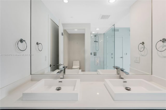 bathroom featuring toilet and dual bowl vanity