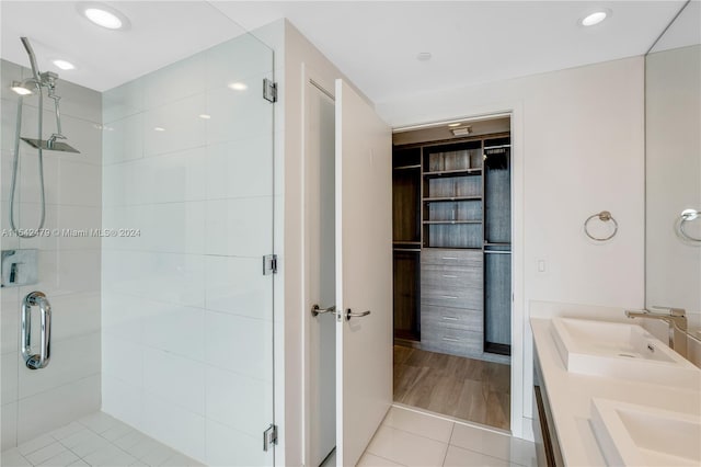 bathroom featuring a shower with door, dual bowl vanity, and hardwood / wood-style floors