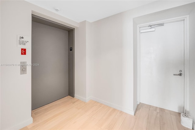 corridor with elevator and light wood-type flooring