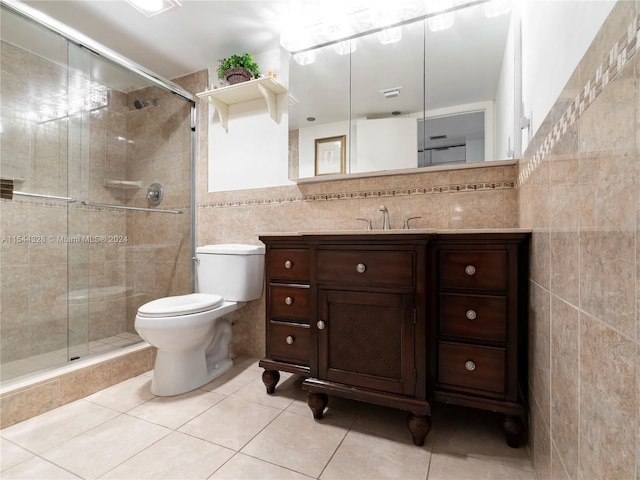 bathroom featuring vanity, tile patterned flooring, toilet, tile walls, and a shower with shower door