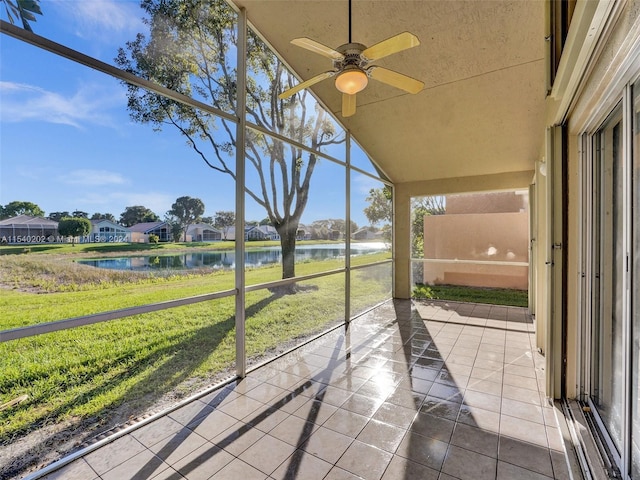 unfurnished sunroom featuring ceiling fan and a water view