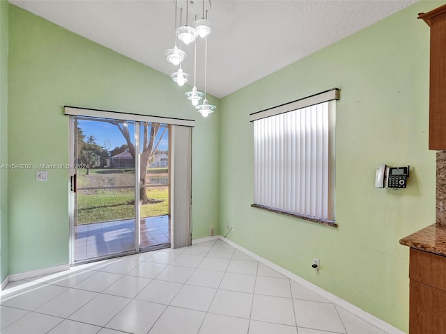 unfurnished room with light tile patterned floors, a textured ceiling, and lofted ceiling