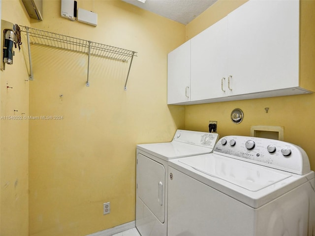 laundry area featuring cabinets, a textured ceiling, and washing machine and clothes dryer