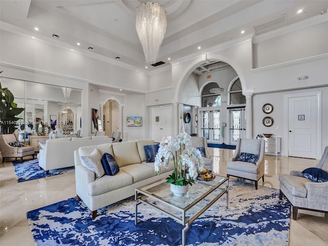 living room featuring ornate columns, crown molding, a high ceiling, and an inviting chandelier