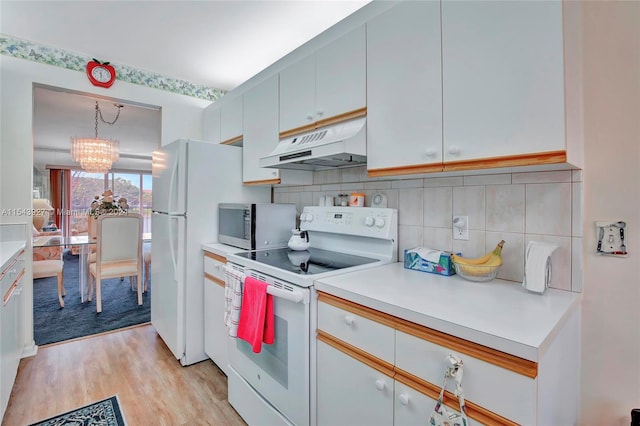 kitchen featuring a notable chandelier, white appliances, tasteful backsplash, hanging light fixtures, and light hardwood / wood-style flooring