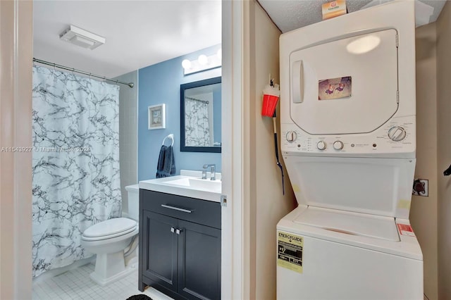 washroom with a textured ceiling, tile flooring, stacked washing maching and dryer, and sink