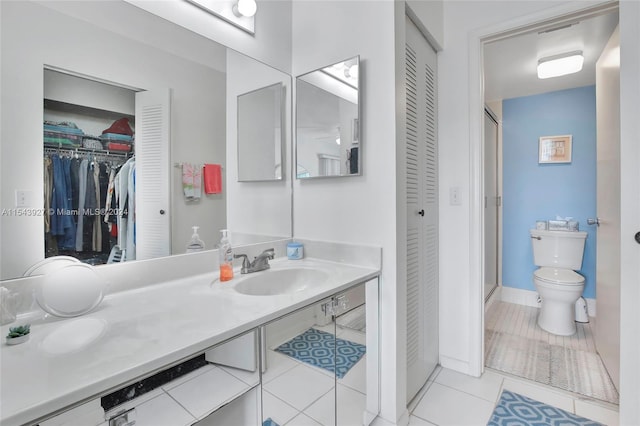 bathroom featuring a shower with shower door, tile floors, toilet, and double sink vanity