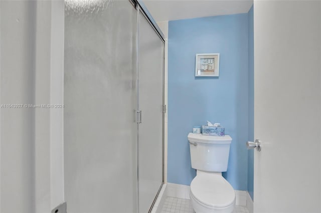 bathroom featuring an enclosed shower, toilet, and tile flooring