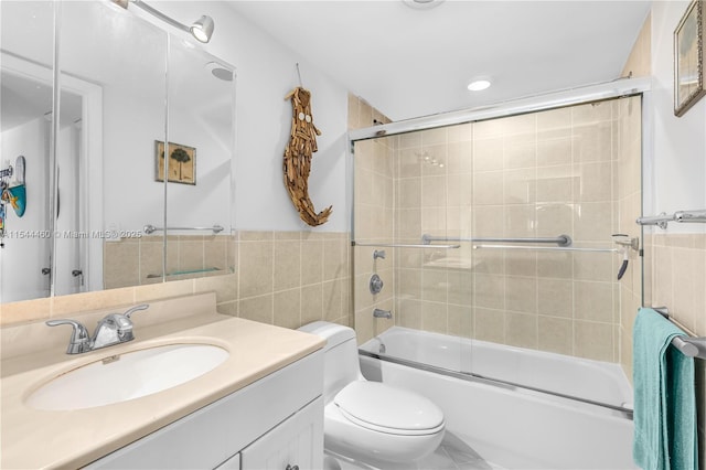 full bathroom with toilet, tile walls, enclosed tub / shower combo, and vanity