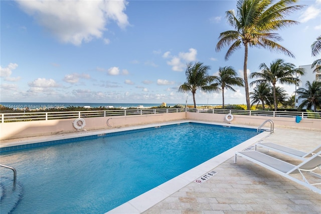 view of pool with a patio area and a water view