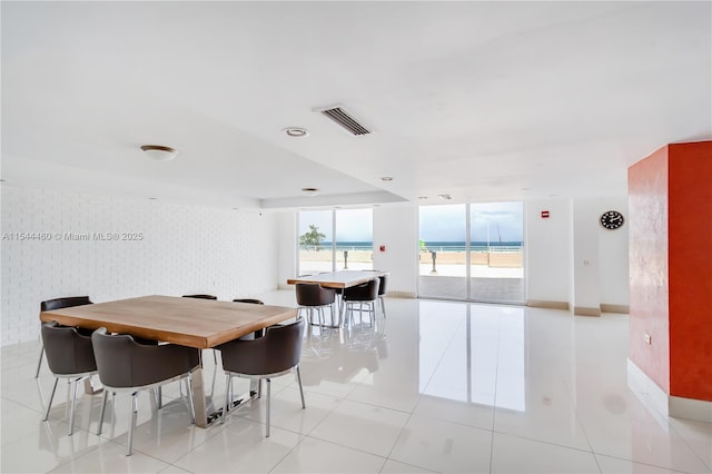 dining area featuring a water view and light tile patterned flooring