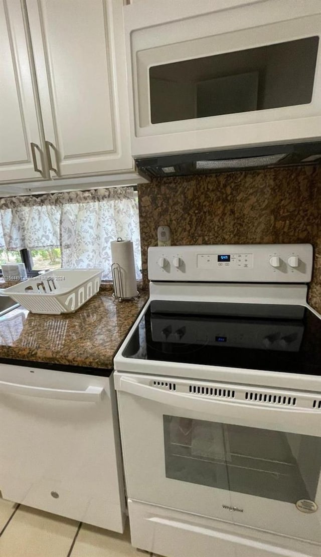 kitchen featuring white cabinetry, white appliances, dark stone counters, and tile patterned flooring