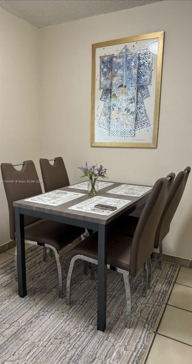 dining area with a textured ceiling and tile patterned flooring