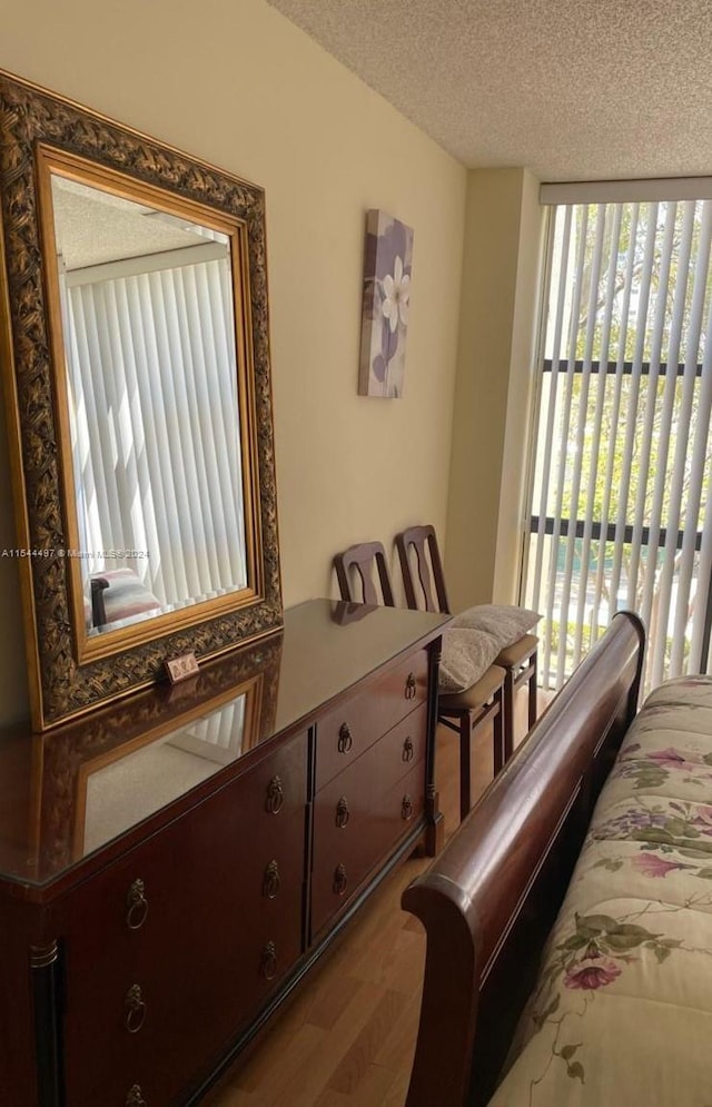 bedroom with hardwood / wood-style floors, a textured ceiling, and access to outside