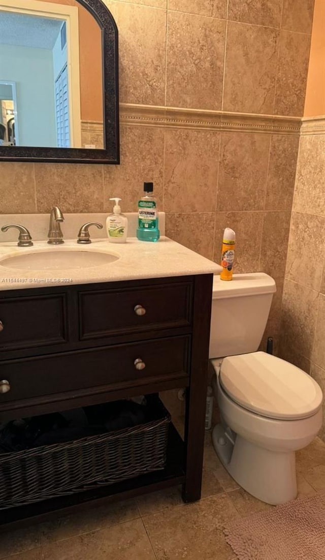 bathroom with vanity, toilet, tile walls, and decorative backsplash