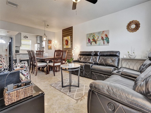 tiled living room with ceiling fan and a textured ceiling