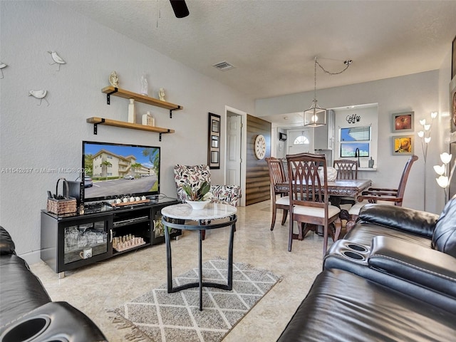 living room featuring ceiling fan and a textured ceiling