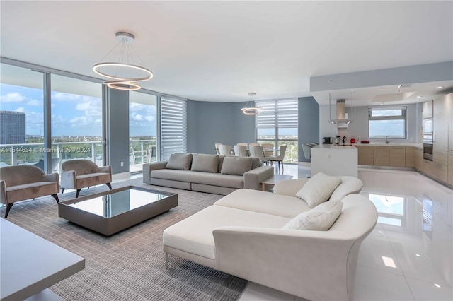 tiled living room with floor to ceiling windows, sink, a chandelier, and a wealth of natural light