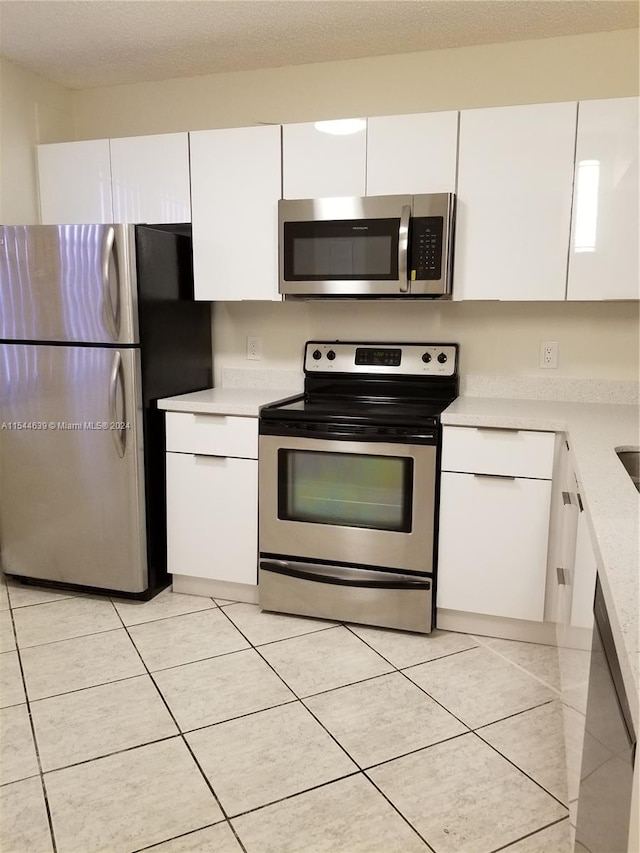 kitchen featuring stainless steel appliances, light tile floors, and white cabinetry