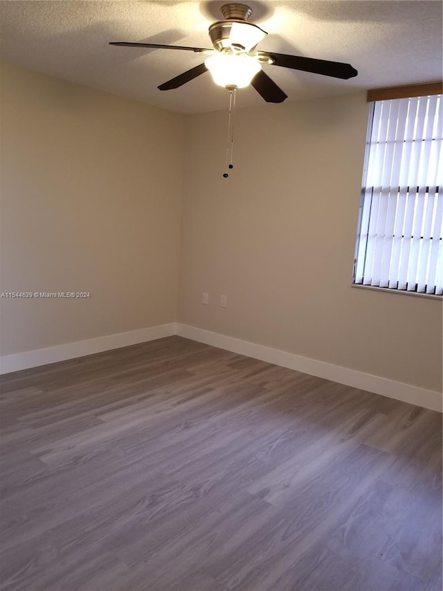 unfurnished room with dark hardwood / wood-style flooring, a textured ceiling, and ceiling fan