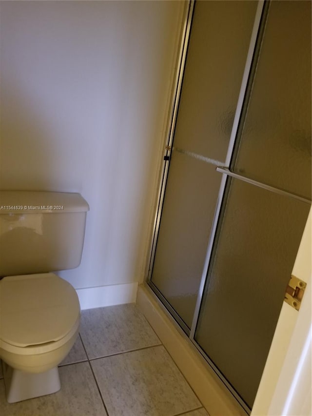 bathroom featuring an enclosed shower, tile floors, and toilet